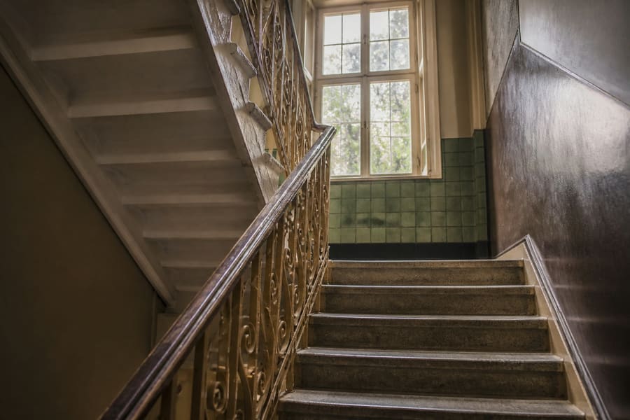 The common staircase of a pre-war walk-up, worn treads and a painted metal banister